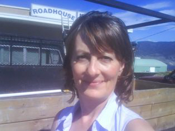 A woman in front of a roadhouse sign.
